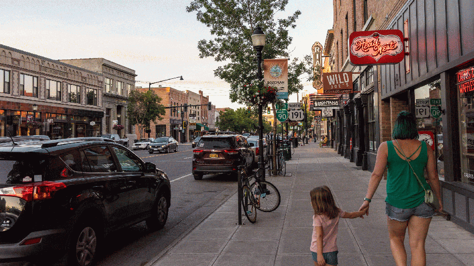 Pedestrians walk along Main Street in Bozeman, Montana, US, on Tuesday, July 19, 2022. Across Montana's 147,000 square miles, the state government recently counted 57 charging stations, most of them clustered in towns and cities rather than along the highway. Photographer: Louise Johns/Bloomberg via Getty Images