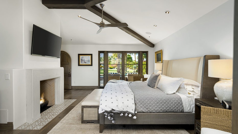 The primary bedroom features hardwood floors, a wood-burning fireplace and a ceiling fan.